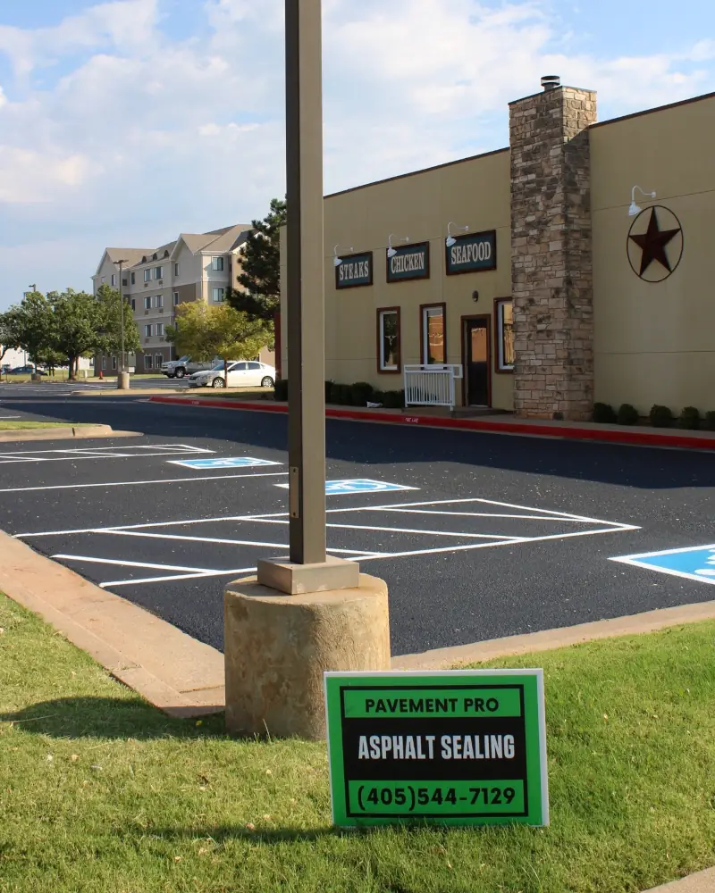 Freshly sealcoated parking lot at Saltgrass Steak House in Oklahoma City with PavementPro Seal sign showing asphalt sealing services.